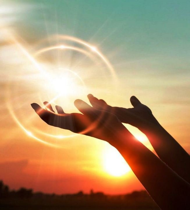 Hands raised in prayer at sunset